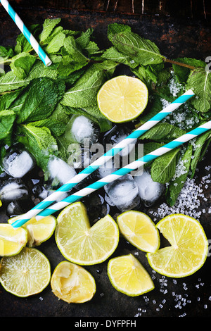 Zutaten für Mojito (frische Minze, Limetten, Eis, Zucker) mit Retro-cocktail Röhren über schwarz. Stockfoto