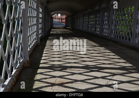 Sonnendurchflutetes Muster Erdgeschoss überdachte Brücke, die hinunter zum Bahnhof führt Stockfoto