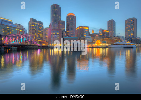 Die Skyline ist beleuchtet und reflektiert das Wasser des Hafens, wie Dämmerung senkt sich in Boston, Massachusetts. Stockfoto