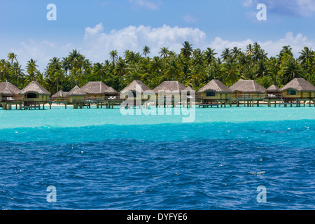 Wasserbungalows über Schichten von blauen und türkisfarbenen Wasser auf Insel Tahaa in Französisch-Polynesien Stockfoto