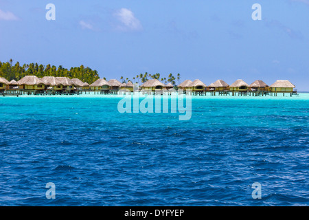 Wasserbungalows über Schichten von blauen und türkisfarbenen Wasser auf Insel Tahaa in Französisch-Polynesien Stockfoto