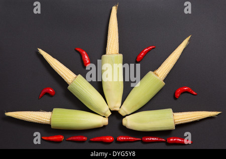 Frische rohe Baby-Maiskolben mit rot-Stem-Paprika auf grauem Hintergrund Stockfoto