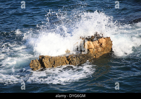 Wellen brechen gegen eine Klippe Stockfoto