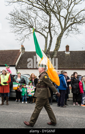 Eine irische Armee Soldat trägt die irische Flagge an der St. Patricks Day Parade in das Dorf der Schären, County Dublin Irland Stockfoto