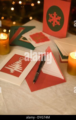 Auswahl von zu Hause gemacht Weihnachtskarten auf einem Tisch mit Umschlägen, Kerzen und einen Füllfederhalter Tinte Stockfoto