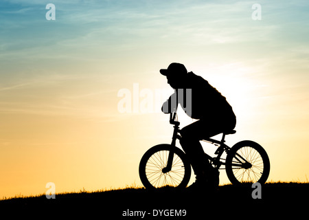 Junger Mann saß auf seinem BMX-Rad. Silhouette Stockfoto