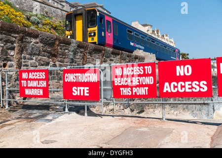 Erstes Great Western Zug vorbei entlang Dawlish Sea Wall vorbei die Warnzeichen, die Verhinderung des Zugriffs auf die beschädigte Deich Stockfoto