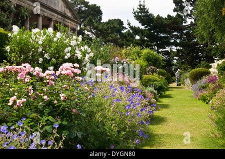 Ein Gärtner bewundert seine Handarbeit an der breiten, von krautigen Pflanzen gesäumten Grenze in den Kiftsgate Court Gardens in den Cotswolds, Gloucestershire, England Stockfoto