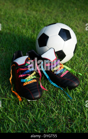 Viel Glück Fußballschuhe Fußball Fußball Stollen geschnürt mit brasilianischen Wunsch Bändern auf grünen Rasen-Fußballplatz Stockfoto