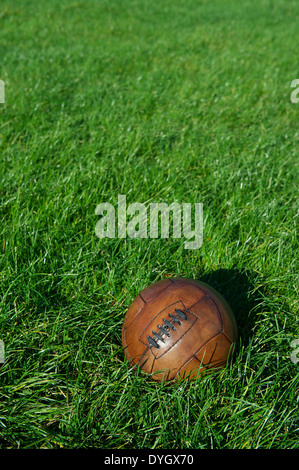 Vintage braun Fußball Fußball sitzt im hellen sonnigen grünen Wiese Stockfoto