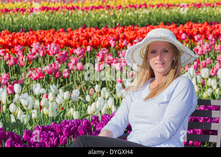 schöne kaukasischen Frau sitzen im Tulpenfeld genießen die Blüten Stockfoto