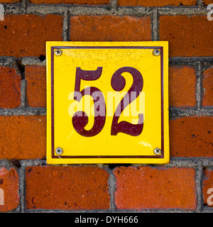 Emaillierte Hausnummer 52. Braune Schrift auf gelbem Hintergrund. Stockfoto