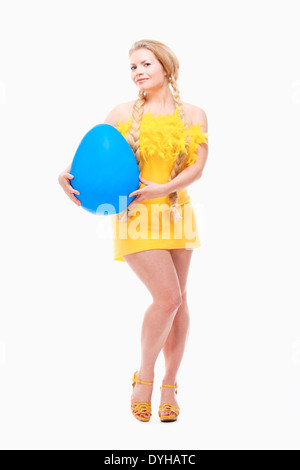 Ostern - junge Frau mit langen blonden Haaren, gelben Kleid und große blaue Ei. Stockfoto