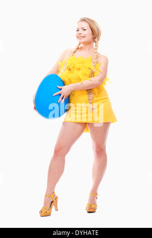 Ostern - junge Frau mit langen blonden Haaren, gelben Kleid und große blaue Ei. Stockfoto