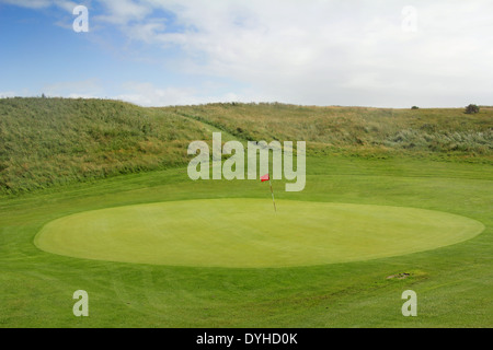 Loch im Golf auf dem grünen Rasen, markiert mit roten Fahne Stockfoto