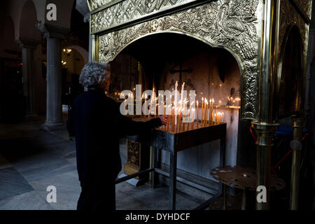 Thessaloniki, Griechenland. 18. April 2014. Eine Frau zündet eine Kerze in der Kirche Saint Demetrius, Patron von Thessaloniki, während ein Karfreitag Prozessionen im nördlichen Hafen von Thessaloniki, Griechenland, auf Freitag, 18. April 2014. Orthodoxe Christen in aller Welt feiern Ostern am Sonntag, den 20. April. Bildnachweis: Konstantinos Tsakalidis/Alamy Live-Nachrichten Stockfoto