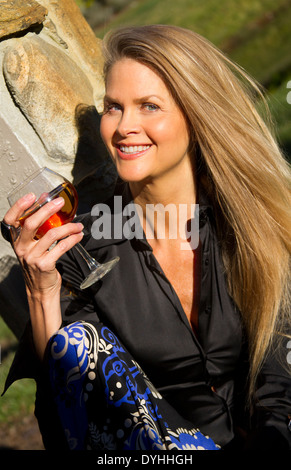 schöne blonde mittlere gealterte Frau trinkt ein Glas Wein in der Sonne Stockfoto