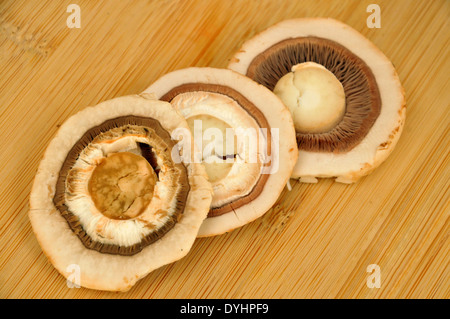 Frische Champignons in Scheiben geschnitten drei Wege auf Holzbrett Stockfoto