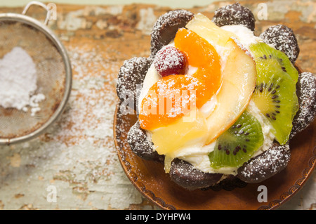 Fruchttorte mit Puderzucker in Holzplatte auf alten Tisch Stockfoto