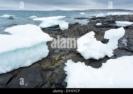 Kanada, Territorium Nunavut, schmelzenden Eisberg entlang der felsigen Küstenlinie auf Sun Island entlang gefrorene Meerenge auf stürmischen Nachmittag Stockfoto