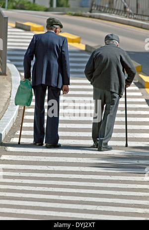 Nebeneinander: zwei alte Männer überqueren einer Straße, die beide mit einem walking-Stick für Unterstützung in Salamanca, Castilla y León, Spanien. Stockfoto