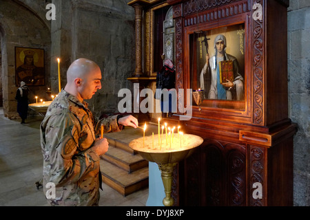 Der georgische Soldat zündet Kerzen, während er in der Kathedrale Svetitshoveli in der historischen Stadt Mtskheta in Georgien betet Stockfoto