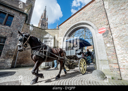 BRÜGGE, Belgien – Touristen erleben das mittelalterliche Ambiente des historischen Zentrums von Brügge von einer traditionellen Pferdekutsche auf Kopfsteinpflasterstraßen aus. Diese beliebte Besichtigungsmethode bietet Besuchern eine romantische Perspektive auf die UNESCO-Weltkulturerbe-Stadt. Die Kutschfahrten pflegen eine jahrhundertealte Tradition des Pferdetransports im historischen Zentrum von Brügge. Stockfoto