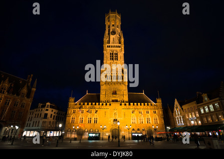 Belfry Markt Brügge Belgien | BRÜGGE, Belgien — Bei Nacht angestrahlt erhebt sich der Belfry über dem Markt im historischen Zentrum von Brügge, sein Ziegelschaft und seine achteckige Krone leuchten golden vor dem dunklen Himmel. Um 1240 begonnen und 1486 mit seiner Sandsteinlaterne vollendet, diente der 272 Fuß (83 m) hohe Turm der mittelalterlichen Handelsstadt sowohl als Wachturm als auch als Schatzkammer, und er beherbergt das 47-Glocken-Karillon, das noch heute geläutet wird. Stockfoto