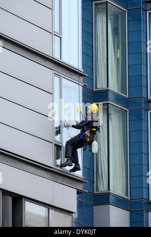 Fenster-Reiniger mit industriellen Seiltechnik Zugang bei der Arbeit an einem Bürogebäude, London Road, Manchester, England, UK Stockfoto