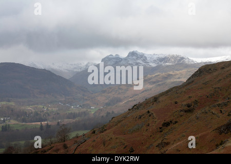 Die schneebedeckten Gipfel des The Langdale Pikes bei einem kalten Frühling Sturm aus Loughrigg fiel Seenplatte Cumbria England Stockfoto