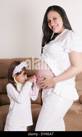 Mädchen untersuchen schwangere Mutter Bauch Stockfoto