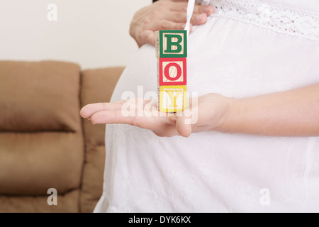 Schwangere Frau, die das Wort "junge" mit Holzklötzchen auf ihre Hand geschrieben Stockfoto