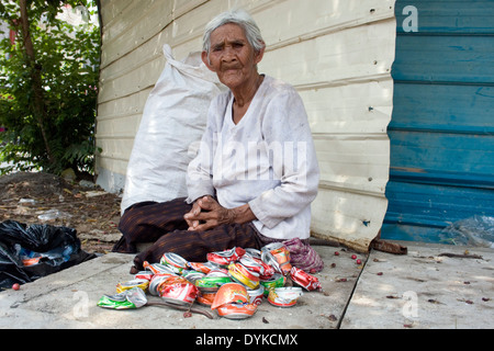 Eine ältere Frau, die in Armut lebenden Menschen ist Softdrink Dosen auf einer Stadtstraße in Kampong Cham, Kambodscha zerkleinern. Stockfoto