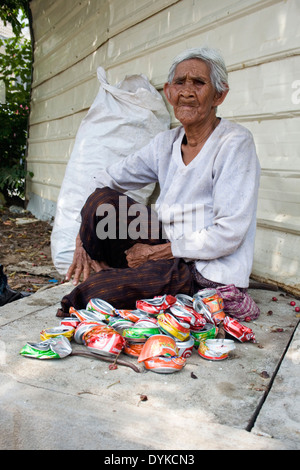 Eine ältere Frau, die in Armut lebenden Menschen ist Softdrink Dosen auf einer Stadtstraße in Kampong Cham, Kambodscha zerkleinern. Stockfoto