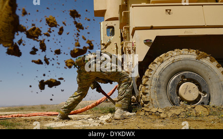 US Air Force Staff Sgt. Kyle McGann digs out a mine-resistant, ambush-protected vehicle from spring mud March 16, 2014 at Kandahar Airfield, Kandahar province, Afghanistan. Stockfoto