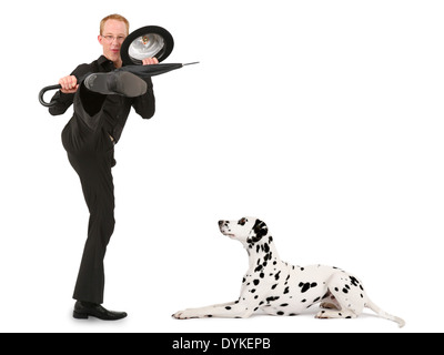 junger Mann mit Melone und Regenschirm treten Dalmatiner Hund Stockfoto