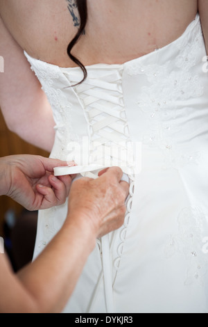 Mutter der Braut anziehen die Spitze Hochzeitskleid für die Braut zurück Stockfoto