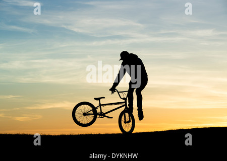 Young Man Tricks auf seinem BMX-Rad zu machen. Silhouette Stockfoto