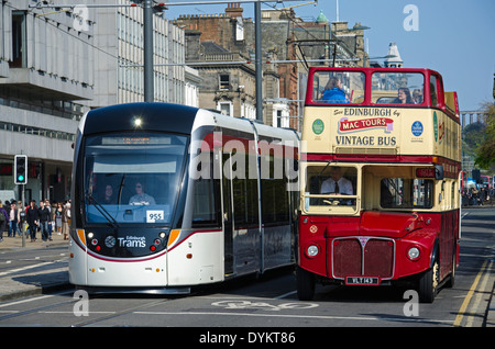 Kontrastierende Verkehrsträger, warten eine elektrische Straßenbahn und ein Vintage-Tour-Bus die Lichter an der Princes Street zu ändern. Stockfoto