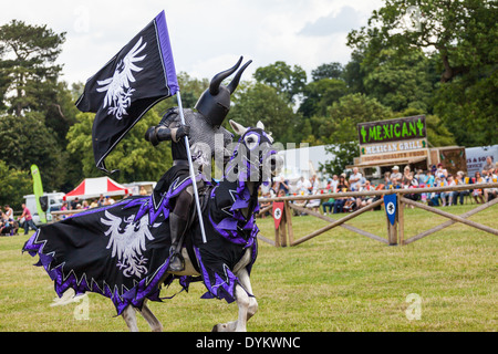 Ritterturniere Ritter in Rüstung in einer mittelalterlichen Messe Reiten ein weißes Pferd auf Shugborough County Event. Stockfoto