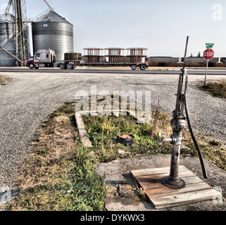 Semi Truck und Trailer neben Getreidesilos und Bahntrasse mit Fracht Autos vorbei, in der Nähe der Stadt Pumpe in Mokassin, Mt geparkt, USA Stockfoto