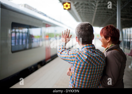 Eltern stehen auf der Plattform in einem Bahnhof winken verabschieden, als der Zug mit ihrem Kind die Station verlässt. Stockfoto