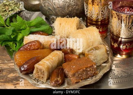 Orientalische süßes Gebäck, Teetassen und Minze Blätter auf einem marokkanischen Tee-Tablett Stockfoto