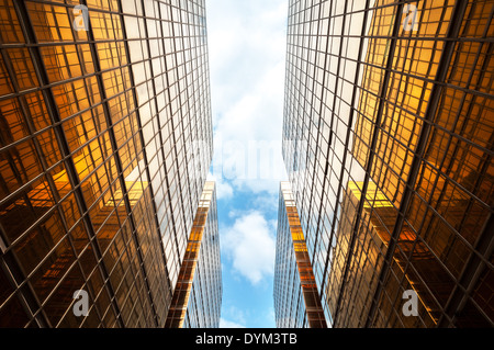 Nach oben Perspektive der symmetrischen zeitgenössische Wolkenkratzer mit blauem Himmel und weißen Wolken Stockfoto