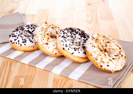 Schokolade und Nüssen Donuts auf Küchentuch auf hölzernen Hintergrund. Kulinarisches süßes Frühstück. Stockfoto