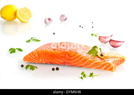 Leckeres Lachssteak mit Zitrone, Petersilie und Knoblauch isoliert auf weißem Hintergrund. Stockfoto