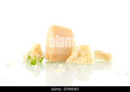 Parmesan-Stücke isoliert auf weißem Hintergrund mit Basilikumblättern. Käse-Hintergrund. Stockfoto