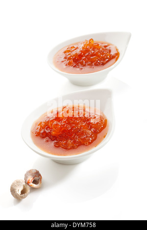 Zwei Schalen mit rotem Kaviar isoliert auf weißem Hintergrund. Dekoriert mit Muschel, köstliche Luxus-Meeresfrüchte-Konzept. Stockfoto