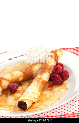 Leckere Pfannkuchen mit Himbeeren und Sahne auf Platte isoliert auf weiss. Traditionelle Süßspeise in rot und weiß. Kulinarisches Stockfoto