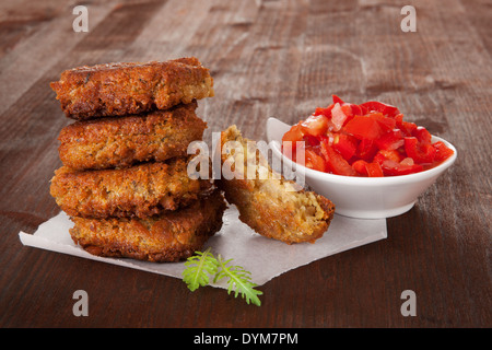 Traditionelle arabische Gerichte, Falafel mit frischen Kräutern und gehackten Tomaten in Schüssel auf braunem Hintergrund aus Holz. Kulinarischen gesunde vegane Stockfoto